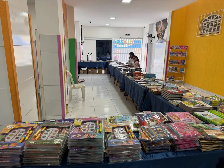 Mesas com livros e kits infantis no Colégio Gato de Botas, em Alagoinhas, Bahia.